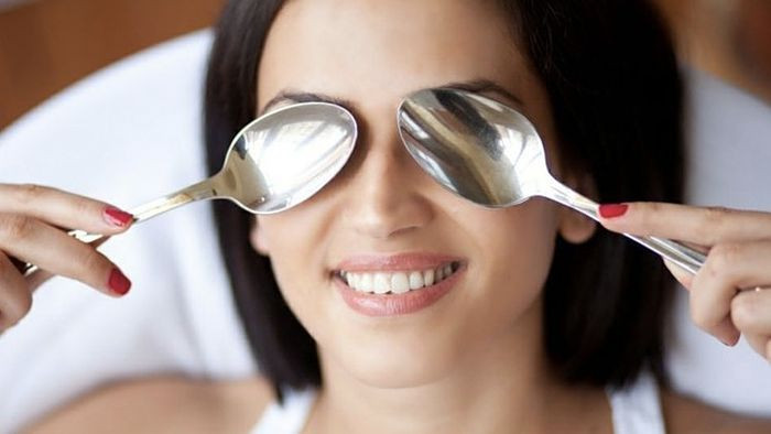 Người phụ nữ dùng muỗng inox massage dưới mắt
